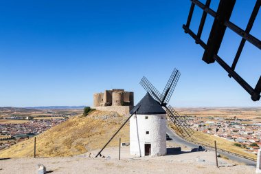 Yel değirmenleri ve kale, Consuegra kasabası ve La Mancha manzarasını izleyen bir tepede duruyor.