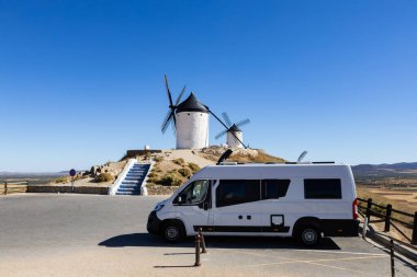Güneşli bir günde klasik İspanyol yel değirmenlerine bakan bir karavan.