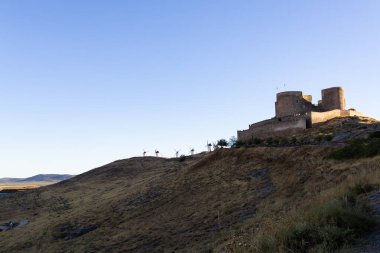 Consuegra kalesi ve tarihi yel değirmenleri berrak bir gökyüzünün altındaki kuru bir tepeye tünemişti.
