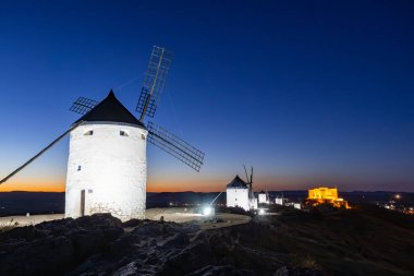 Geleneksel İspanyol yel değirmenleri ve kale alacakaranlıkta parlak bir şekilde aydınlatılır.