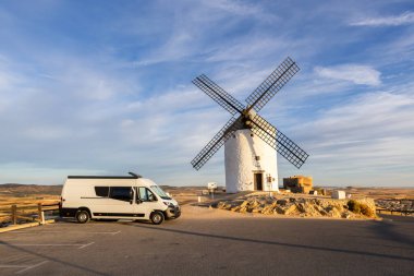 Geleneksel İspanyol yel değirmeninin yakınına park edilmiş karavan seyahat, macera ve yol gezisini temsil ediyor.