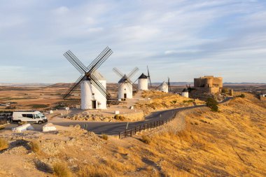 İspanya, La Mancha, Consuegra 'da bir tepenin üzerinde duran tarihi rüzgar değirmenleri ve şato