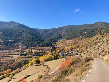 İspanyol Pireneleri 'nin sonbahar vadisinde yuva yapmış büyüleyici köye giden dolambaçlı dağ yolu.