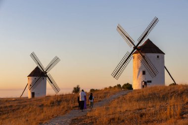 Mota del Cuervo, İspanya; 21 Eylül 2025: Grup altın saatinde bir tepedeki tarihi İspanyol yel değirmenlerine hayran olan bir yolda yürüyor