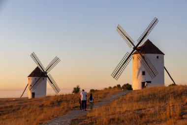 Mota del Cuervo, İspanya; 21 Eylül 2025: Aile altın saat boyunca tepede Mota del Cuervo geleneksel yel değirmenlerinin tadını çıkarıyor ve keşfediyor