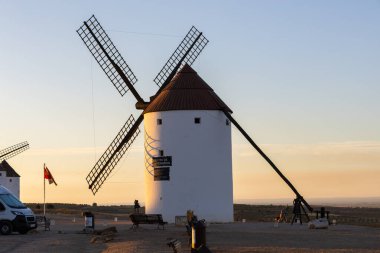 Mota del Cuervo, İspanya; 22 Eylül 2025: Geleneksel La Mancha yel değirmeni sıcak bir günbatımı gökyüzüne karşı dik duruyor