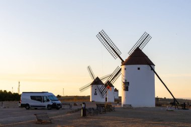 Mota del Cuervo, İspanya; 22 Eylül 2025: Campervan sıcak bir akşam gökyüzünün altında tarihi İspanyol yel değirmenlerinin yakınına park etti