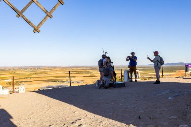 Consuegra, İspanya; 23 Eylül 2025: Panoramik manzara ve La Mancha 'daki bir tepenin tepesinde anıt yakalayan bir grup turist