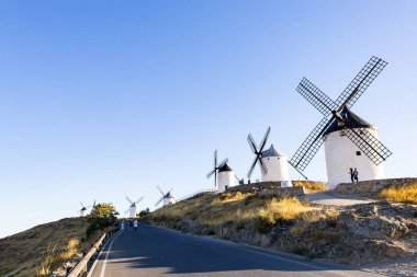 Consuegra, İspanya; 23 Eylül 2025: Geleneksel İspanyol yel değirmenleri açık mavi gökyüzünün altında bir Consuegra yamacını oluşturarak turistleri cezbediyor