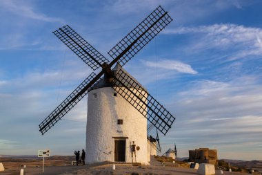 Consuegra, İspanya; 24 Eylül 2025: Geleneksel İspanyol yel değirmenleri gün batımında mavi gökyüzüne karşı La Mancha manzarası