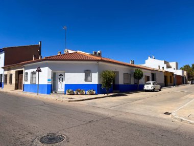 Campo de Criptana, İspanya; 22 Eylül 2025: Campo de Criptana 'da sakin güneşli bir sokakta mavi çizgili geleneksel evler