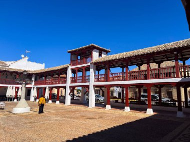 Puerto Lapice, İspanya; 23 Eylül 2025: Tarihi Plaza de la Constitucion 'da yürüyen kadın, geleneksel arcaded mimariye sahip