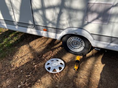 Puigcerda, İspanya; 21 Nisan 2023: Karavan tekeri, yerde bir jant kapağı, lastik ve matkap gösteriyor