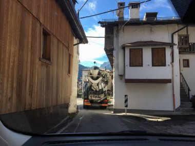 Val di Zoldo, İtalya; 4 Ekim 2017: Belluno 'daki geleneksel binalar arasında dar bir sokaktan geçen çimento karıştırıcı kamyon