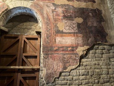 La Vall de Boi, İspanya; 26 Temmuz 2021: Roma freski antik bir taş duvarı süslüyor ve İspanya 'nın La Vall de Boi kentindeki bir kilisenin kemerli kapısı