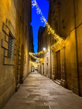 Barselona, İspanya; 3 Aralık 2023: Gotik Çeyrek Sokak, eski binalarını geceleri geleneksel sicim lambalarıyla aydınlatıyor