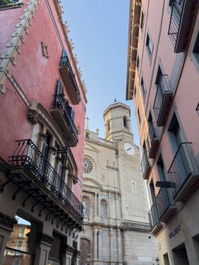 Olot, İspanya; 25 Haziran 2025: Olot, Katalonya, İspanya 'daki tarihi Sant Esteve Kilisesi' ni çerçeveleyen renkli bina cepheleri