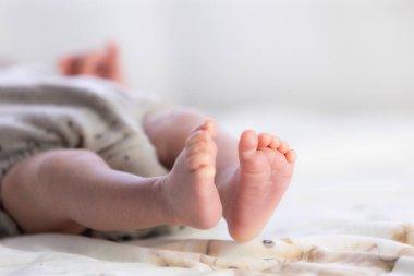 Yeni doğmuş bebek ayakları yumuşak bir battaniyede dinleniyor, erken çocukluğu ve yeni hayatı temsil ediyor.