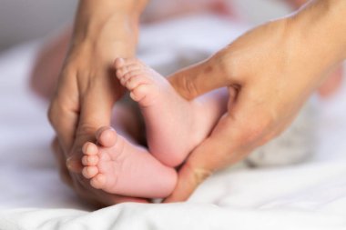 Annenin elleri nazikçe dokunur ve bebek ayaklarına dokunur.