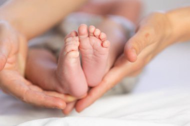 Ebeveynler, iki haftalık bir bebeğin ayaklarını nazikçe destekliyor.