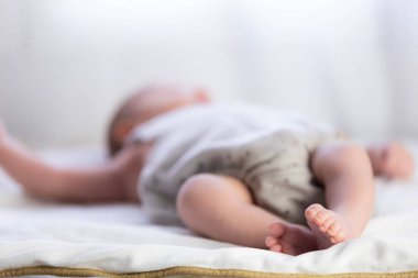 Yeni doğmuş erkek bebek, beyaz bir battaniyenin üzerinde huzur içinde uyuyor. Değerli küçük ayaklarını gösteriyor.
