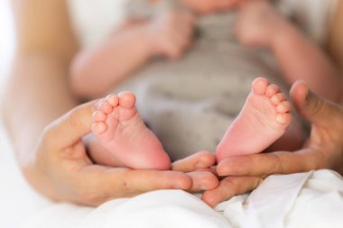 Ebeveyn elleri nazikçe kucaklar küçük bebek ayaklarını