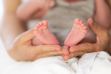 Yeni doğan bebeğin küçük ayaklarını tutan ebeveyn, ilgiyi, sevgiyi ve yeni hayatı simgeliyor.