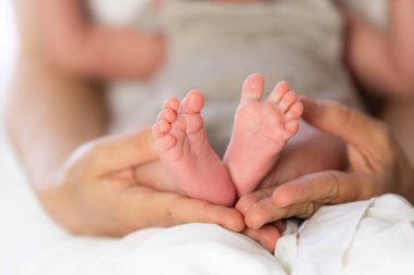 Ebeveyn elleri iki haftalık küçük bebek ayaklarını nazikçe tutuyor, yeni hayatı ve aile sevgisini simgeliyor.