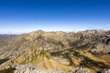 Pireneler, kayalık arazi üzerinde açık mavi gökyüzü ile panoramik bir manzara oluşturur.