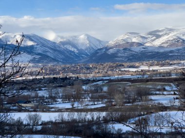 Vadi kasabası karla kaplı tarlalar ve etkileyici dağlar arasında kışın gökyüzü altında.
