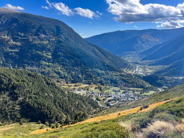 Fransa 'nın Porte Puymorens şehrinde mavi gökyüzü ve bulutları olan bir vadide köy ve dağlar.