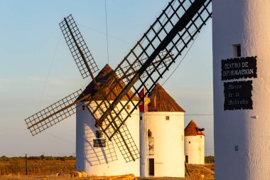 La Mancha 'daki geleneksel İspanyol yel değirmenleri gün batımında kırsal bir arazide duruyor.