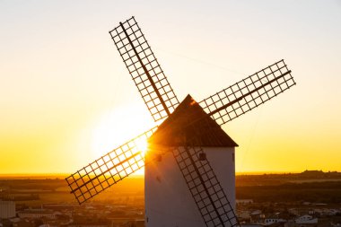 Yel değirmeni, La Mancha bölgesinde gün batımında parlak bir güneş patlamasına karşı dimdik ayakta duruyor.