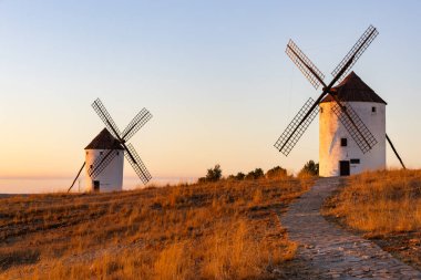 La Mancha 'nın altın saatine bakan iki tarihi yel değirmeni.