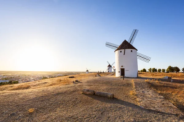 Geleneksel İspanyol yel değirmenleri beyaz yapılar ve hareketli bir gökyüzü altında dönen yelkenler içerir.