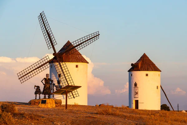 Günbatımında Don Kişot anıtı olan bir tepede duran tarihi İspanyol yel değirmenleri.