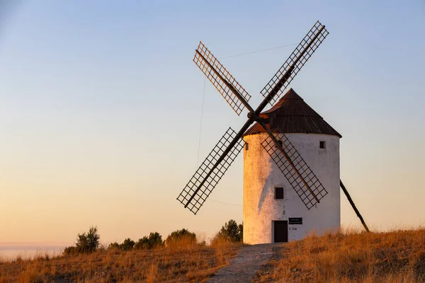 Geleneksel İspanyol yel değirmeni La Mancha tepesinde altın saat ışığı