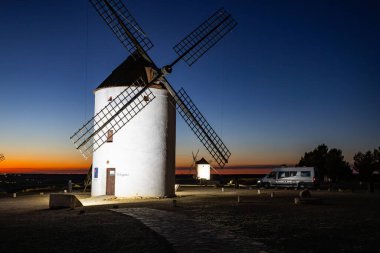 İspanya, Mota del Cuervo 'daki manzarayı canlı bir alacakaranlık altında noktalayan beyaz rüzgar değirmenleri