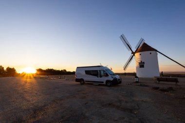 Mota del Cuervo ve Sunset 'te geleneksel bir İspanyol yel değirmeninin yanına park edilmiş beyaz bir karavan.