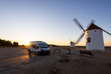 Campervan gün batımında La Mancha bölgesinde ikonik yel değirmenlerinin yanına park etti.