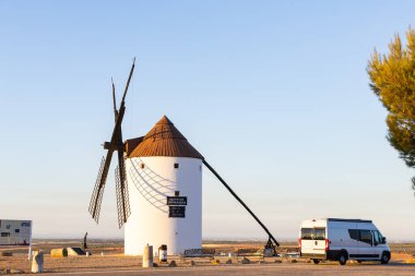 Beyaz İspanyol yel değirmeni gün batımında La Mancha 'da bir karavanın yanında duruyor.