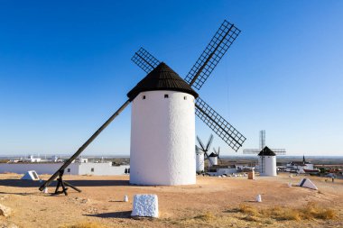 Beyaz yel değirmenleri, kurak araziyi açık mavi gökyüzüne lekeleyerek Don Kişot 'un maceralarını anımsatıyor.