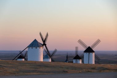Geleneksel yel değirmenleri, gün batımında kuru bir arazide, La Mancha 'nın bir sembolü.