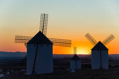 Geleneksel İspanyol yel değirmenleri canlı turuncu ve sarı günbatımı gökyüzüne karşı