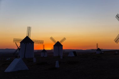 Geleneksel İspanyol yel değirmenleri canlı bir turuncu ve mavi gökyüzüne karşı siluetlendi