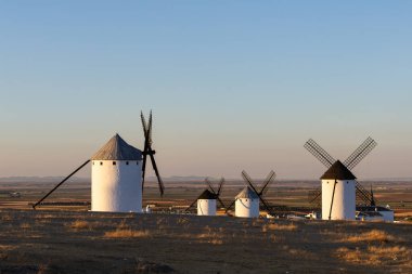 Günbatımında La Mancha 'da bir tepenin üzerinde duran tarihi İspanyol yel değirmenleri