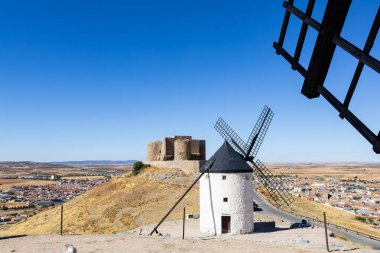 Beyaz yel değirmenleri ve İspanya 'nın Consuegra ovasına bakan tarihi bir kale.