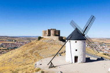 Geleneksel yel değirmeni ve kale La Mancha 'daki Consuegra kasabasına bakan bir tepenin üzerinde duruyor.