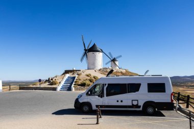 İspanya, Consuegra 'nın ikonik beyaz yel değirmenlerinin yanına park edilmiş bir karavan.