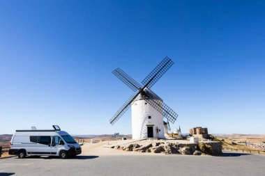 Consuegra 'da geleneksel bir İspanyol yel değirmeninin yanına park edilmiş beyaz bir karavan.